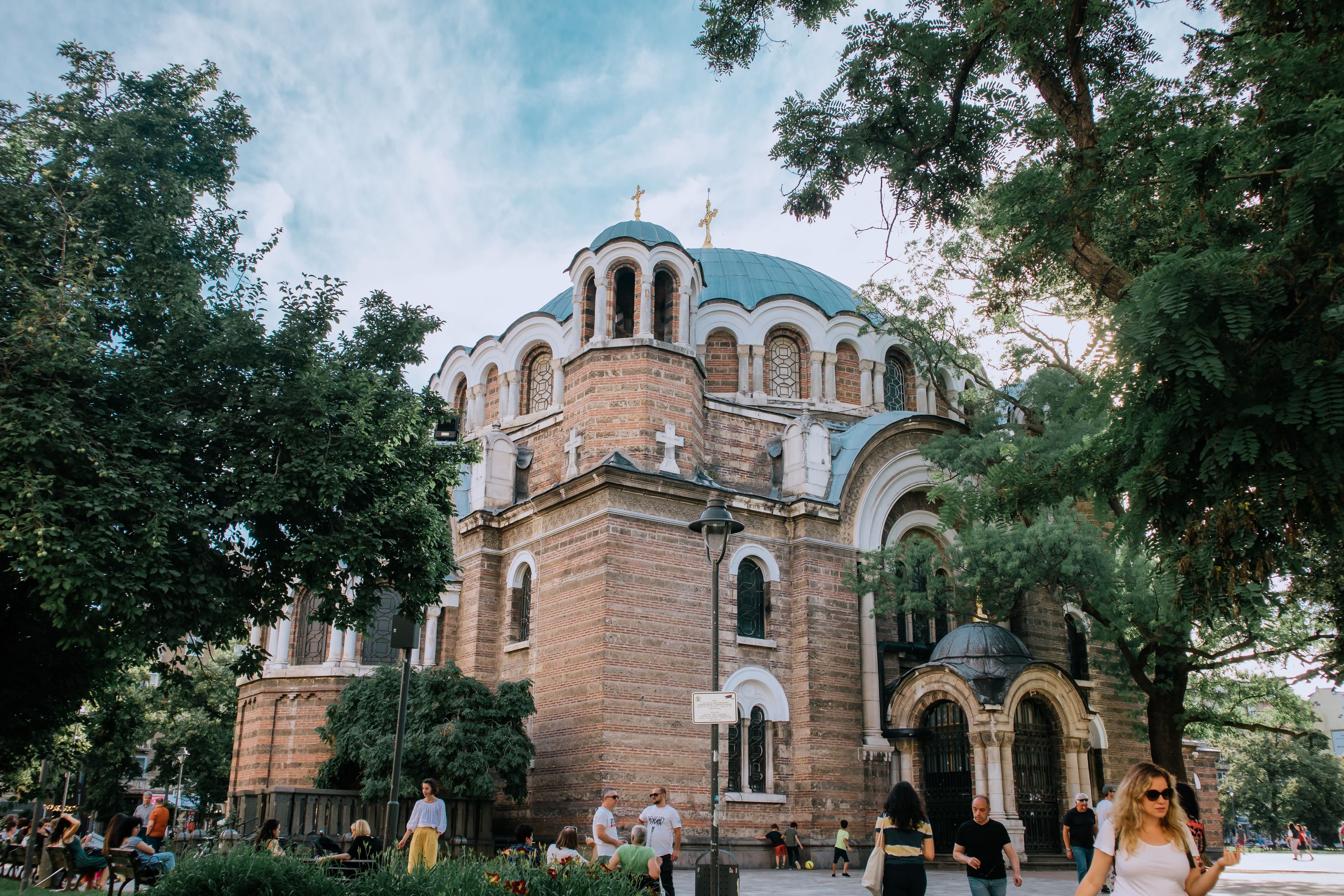 A historic church surrounded by lush green trees in a central Sofia park in summer