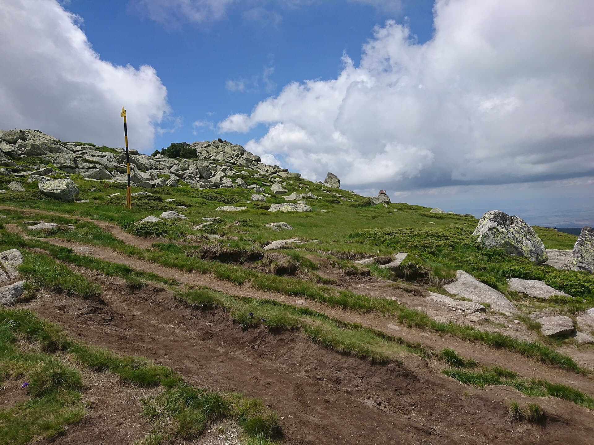 A rocky hiking trail near the summit of Vitosha mountain, under a blue sky with clouds