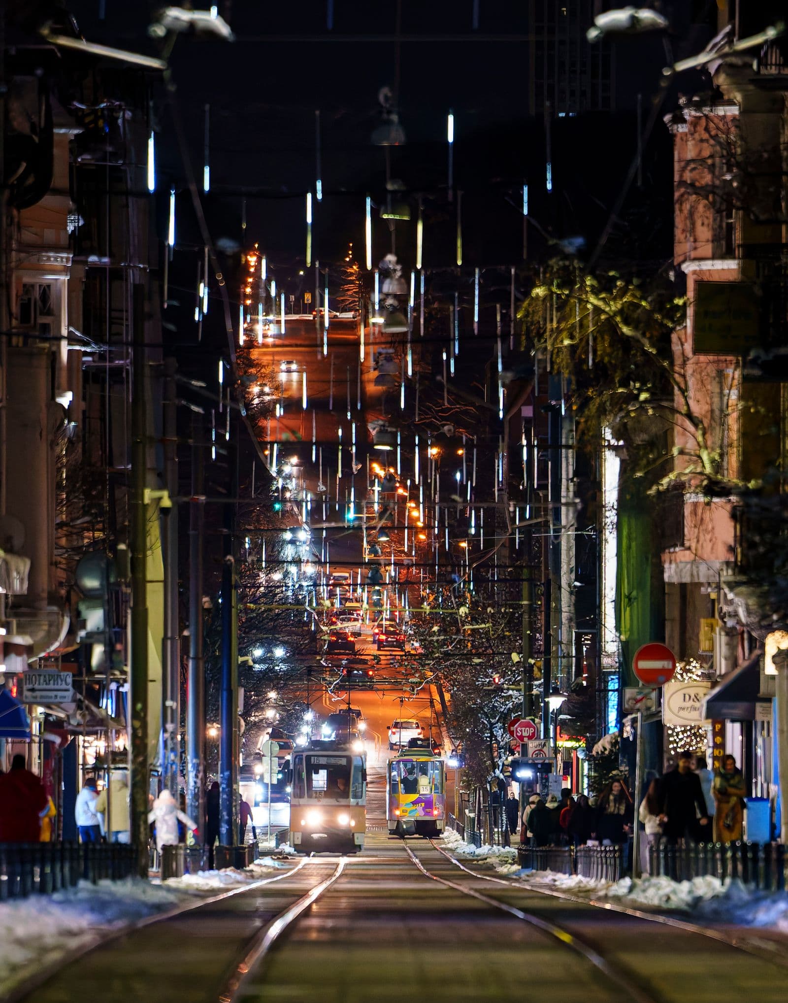 A lively central Sofia street at night, lit up with city lights and a passing tram